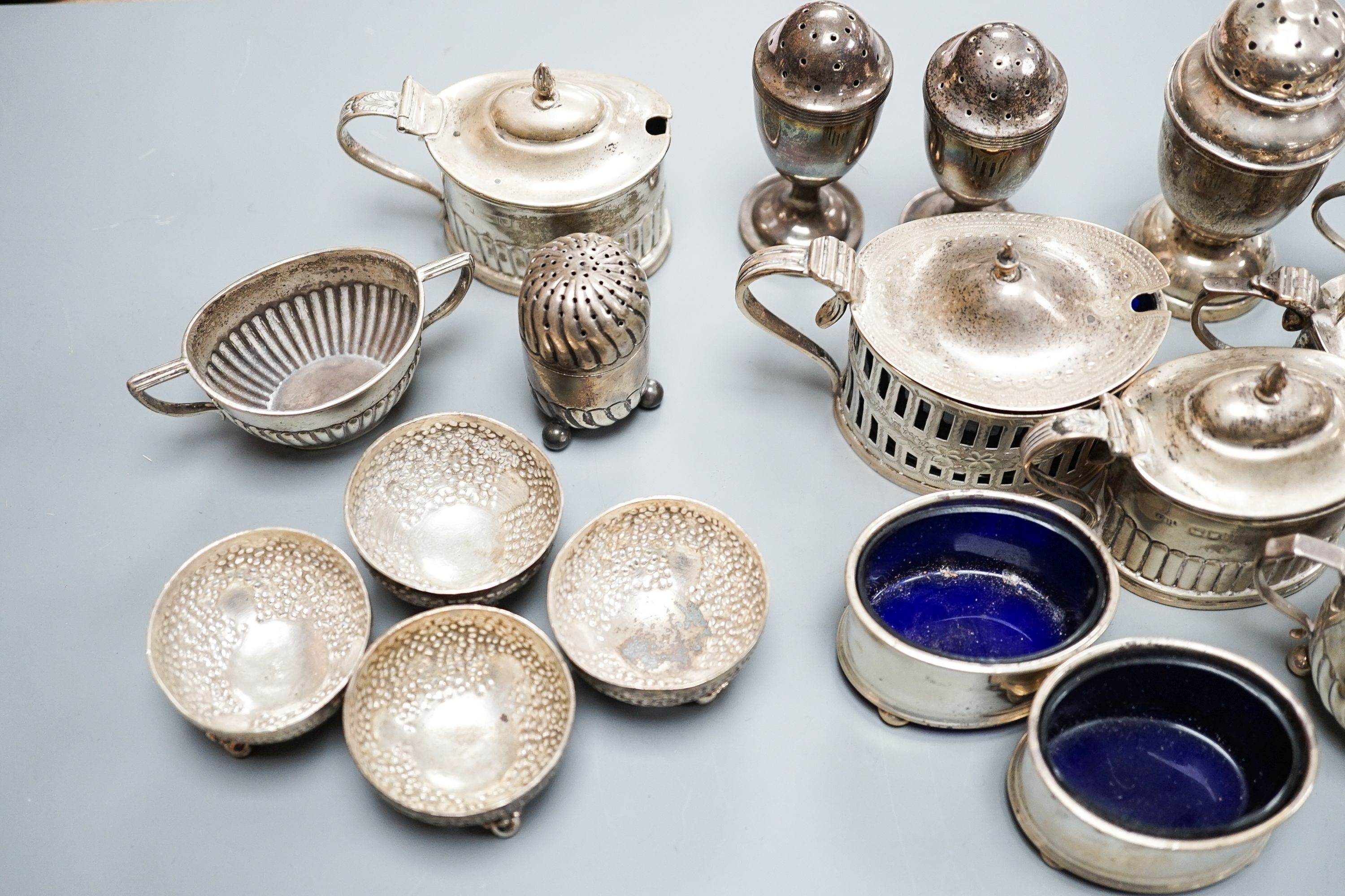 A mixed group of assorted mainly early 20th century silver condiments, including mustard pots, salts and pepperettes, two napkin rings and four plated salts, some lacking liners.